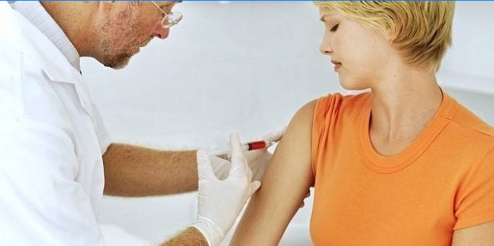 Läkaren gör en injektion i flickans underarm