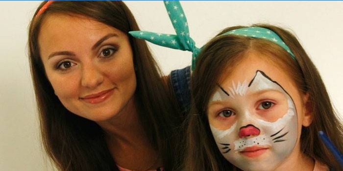 Flicka med ansiktsmålning av katt och mamma
