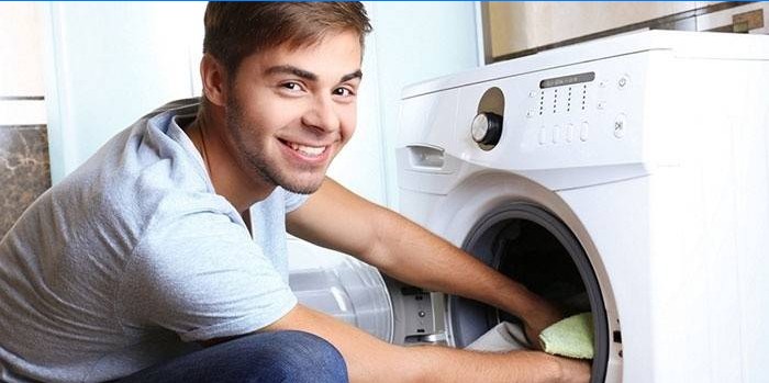 Killen sätter saker i trumman på en tvättmaskin