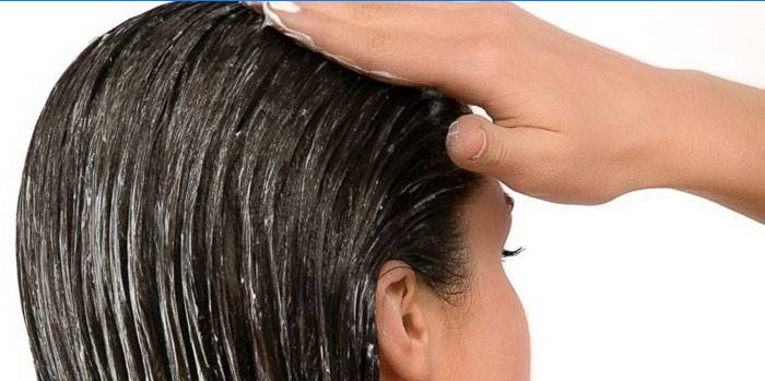 Flickan applicerar en balsam i håret