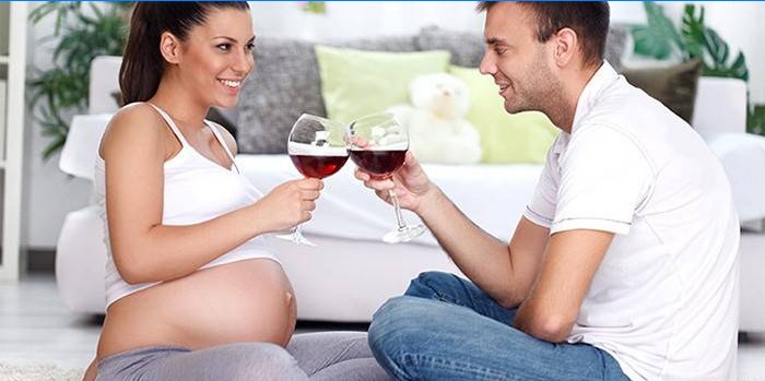 Gravid kvinna dricker vin i sällskap med en man