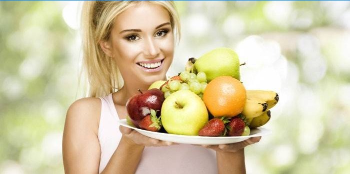 Flickan håller en maträtt med frukter och bär.